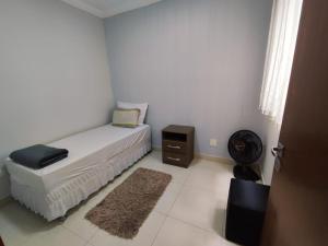um quarto branco com uma cama e uma mesa de cabeceira em Residencia Cidade Verde 14 em Maringá