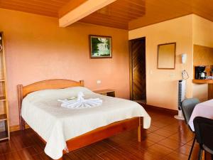 um quarto com uma cama com um cobertor branco em Los Tucanes Lodging em El Castillo de La Fortuna