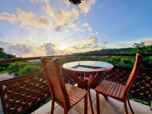 d'une table et de deux chaises sur un balcon avec vue sur le coucher du soleil. dans l'établissement Hotel Ficus - Monteverde, à Monteverde Costa Rica