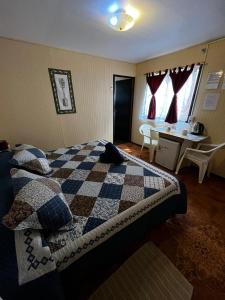 Un dormitorio con una cama con una manta a cuadros. en Camping Hostal Tipanie Moana Aeropuerto Centro, en Hanga Roa