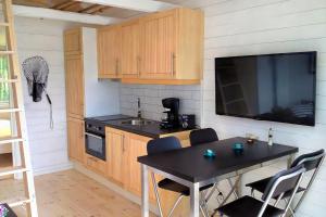 uma cozinha com uma mesa e uma televisão e uma mesa e cadeiras em Sjöstugan, Solviken em Rockneby