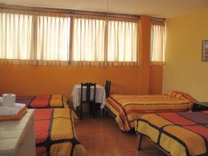 a hotel room with three beds and a table at Casa de Mama Cusco 2-The Ecohouse in Cusco