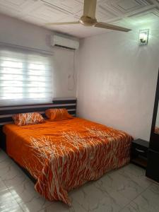 um quarto com uma cama com um edredão laranja em Deoyem Place em Ikorodu