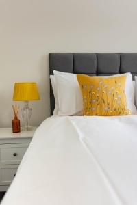 um quarto com uma cama branca e uma mesa de cabeceira com um candeeiro em Lovely 2 bed house in Pitlochry em Pitlochry