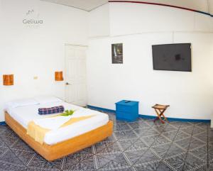 Hotel Geliwa في توريالبا: غرفة نوم بسرير وتلفزيون بشاشة مسطحة