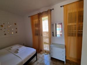 ein Schlafzimmer mit einem Bett, einer Kommode und einem Fenster in der Unterkunft Corfu Dream Holidays Villas 2-4 in Glyfada