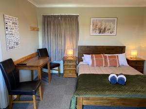 a bedroom with a bed and a desk with two slippers at Hokitika Holiday Park in Hokitika