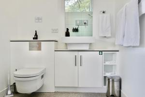 a white bathroom with a toilet and a sink at Eaglehawk Pavilions in Eaglehawk Neck