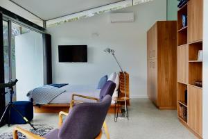 a bedroom with a bed and two chairs and a tv at Eaglehawk Pavilions in Eaglehawk Neck