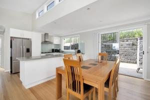 a kitchen and dining room with a wooden table and chairs at Banksia by the Sea Gerroa in Gerroa