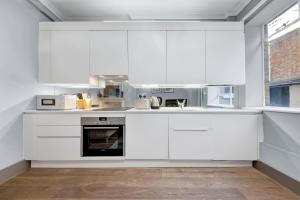 a white kitchen with white cabinets and appliances at SERCASA - Cleveland Residence - Fitzrovia in London