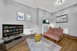 a living room with a couch and a flat screen tv at SERCASA - Cleveland Residence - Fitzrovia in London