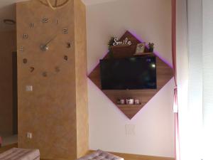 a living room with a large clock and a tv at Apartman M2 Titova Vila in Palisat