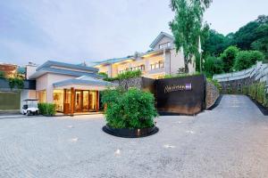 a house with a bush in the middle of a driveway at Radisson Blu Resort Dharamshala in Dharamshala