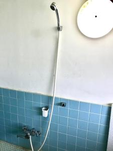 a shower in a bathroom with a blue tile wall at Astuto Riders House in Annaka