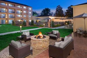 a patio with chairs and a fire pit in front of a building at Sonesta Select Raleigh Durham Airport Morrisville in Morrisville