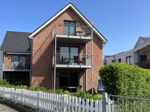 a brick house with a white fence in front of it at Neehuus Wohnung 5 in Borkum
