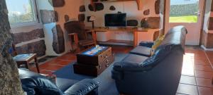 uma sala de estar com um sofá de couro e uma televisão em Casa da Vitória em Santa Cruz da Graciosa