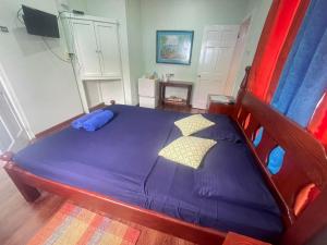 a bedroom with a bed with purple sheets and pillows at Miller's Guest House in Buccoo