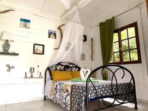 LODGE PAMPLEMOUSSE avec PISCINE privative , dans parc calme à 500 m plage في لو كاربيت: غرفة نوم مع سرير وحوض استحمام