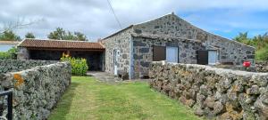 ein altes Steinhaus mit einer Steinmauer in der Unterkunft Casa da Vitória in Santa Cruz da Graciosa