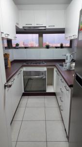 a kitchen with white cabinets and a large window at departamento santiago centro frente club hipico y movistar arena in Santiago