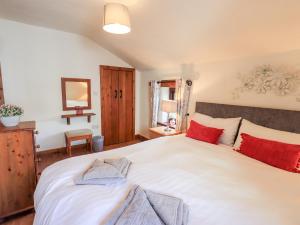 a bedroom with a large white bed with red pillows at Bobbin Cottage in Staveley