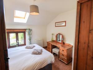 a bedroom with a bed and a desk and a window at Gowan Cottage in Staveley