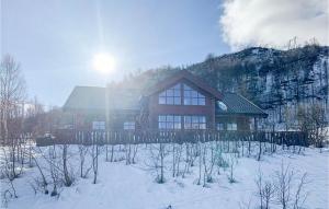 Stunning Home In Norheimsund With House A Mountain View في نورهايمسوند: منزل في الثلج امام جبل