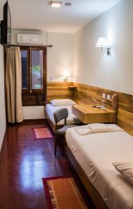 a room with two beds and a desk in it at Hotel Cuatro Pinos in Oberá