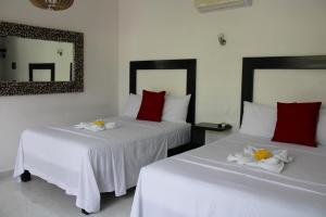 two beds in a room with white and red pillows at Casa Zazil in Bacalar