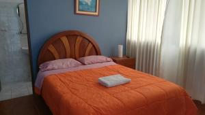 - une chambre avec un lit et une couverture orange dans l'établissement Hospedaje Fremiott, à Huanchaco