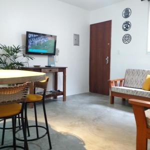 a living room with a tv and a table and chairs at Apartamento Dona Frida Prainha com WiFi pé na areia in Caraguatatuba