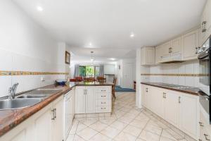 a kitchen with white cabinets and a sink at 4/84 Lawson Street - Beach Haven 4 in Byron Bay