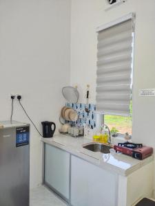 encimera de cocina con fregadero y ventana en Wanna Homestay, en Jertih