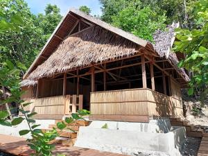 une cabane avec un toit de chaume et des escaliers à l'avant dans l'établissement Warahnus dive homestay, à Kri