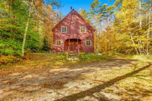 a red barn in the middle of a dirt road at Cozy Cabin in the Woods in Londonderry