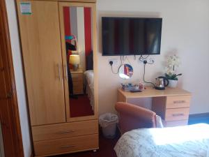 a bedroom with a dresser with a television and a dresser with a desk at Fox and Hounds Country Inn in Willingham