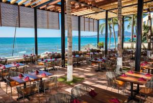 a restaurant on the beach with tables and chairs at Condo at Krystal Grand Resort in Bucerías