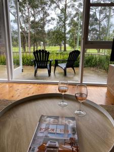 two wine glasses sitting on a table with a magazine at Beach House On Golf in Mollymook