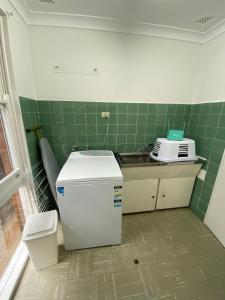 a small kitchen with a sink and a refrigerator at Beach House On Golf in Mollymook