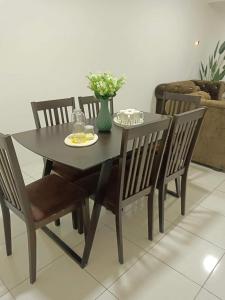 a dining room table and chairs with a black table and flowers at D'Irish Homestay Wakaf Che Yeh in Kota Bharu