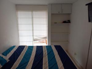 Un dormitorio con una cama azul y blanca y una ventana en Minidepartamento en San Bartolo - VISTA AL MAR, en San Bartolo