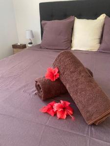 a bed with two towels and two flowers on it at Bora Bora Fare Sophia in Bora Bora