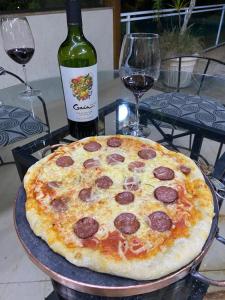 una pizza sentada en una mesa junto a una botella de vino en Aconchegante casa com piscina e lazer completo en Teresópolis