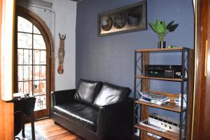 un sofá de cuero negro en una sala de estar con ventana en The Fox Hostel, en Santiago