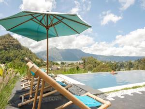 a group of chairs and an umbrella next to a swimming pool at Batur Cliff Panorama in Baturaja