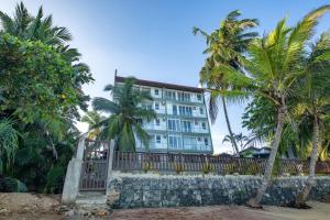 a building on the beach with palm trees at Grand Samudra Hotel in Tangalle