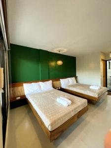 2 Betten in einem Zimmer mit grüner Wand in der Unterkunft TEZA Resort in Bantayan