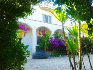 a white house with purple flowers in front of it at B&B Santa Sabina in Torre Santa Sabina
